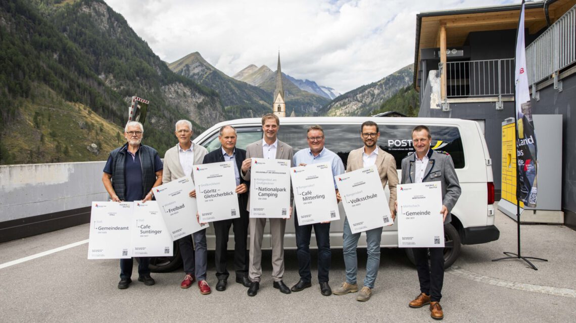Sieben Männer mit Schildern vor einem Postbus im Ötztal
